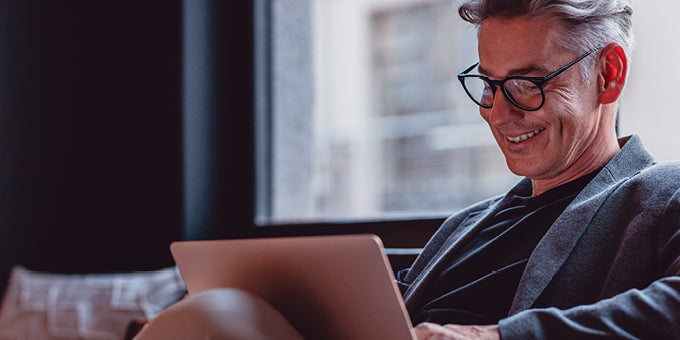Man using a laptop while sitting on a couch with a blurred background