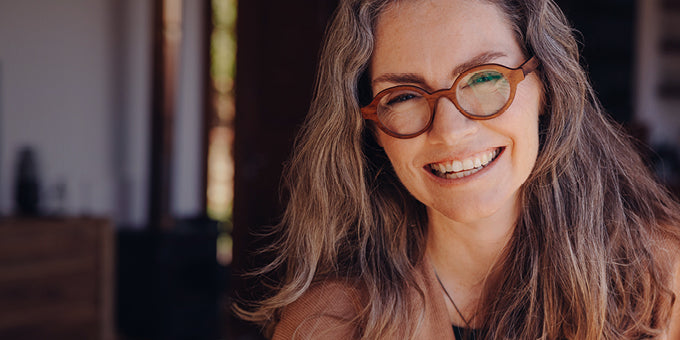 Middle-aged woman wearing glasses with a blurred indoor background